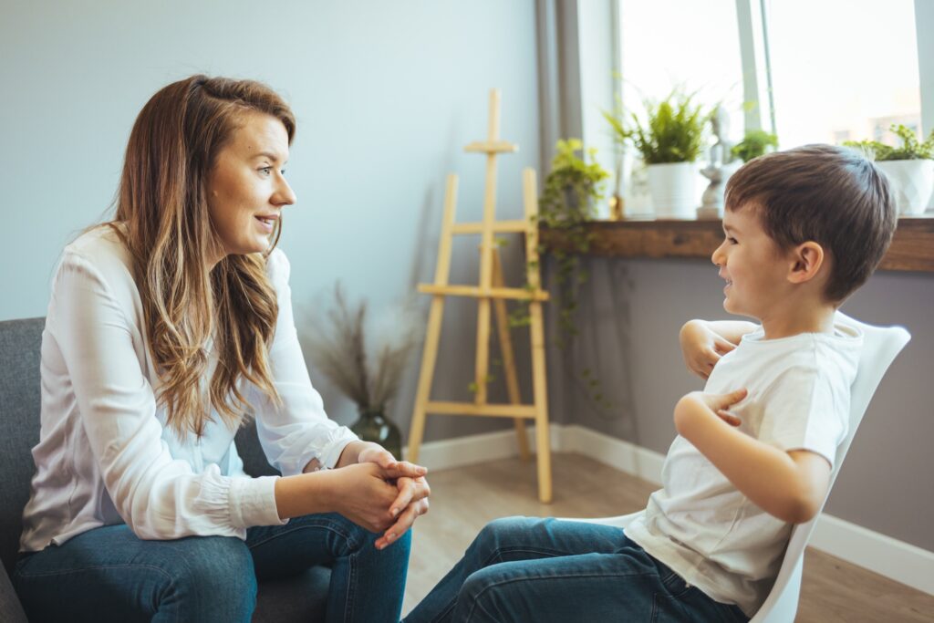 Young boy having therapy with a child psychologist. Shot of a young child psychologist talking with a boy. Friendly young child psychologist talking with little boy suffering from emotional disorder in bright office